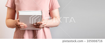 Hand holding closed paper book in hard cover. Banner background 105008716