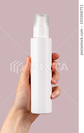 Hand holding spray bottle mockup, blank beauty product on pink background 105008751