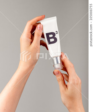 Holding B3 facial cream in tube. Niacin cosmetic product 105008755