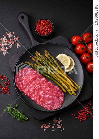 Delicious nutritious breakfast consisting of sliced sausage, asparagus, salt, spices and herbs Delicious nutritious breakfast consisting of sliced sausage, asparagus, salt, spices and herbs 105009396
