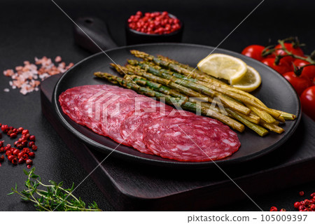Delicious nutritious breakfast consisting of sliced sausage, asparagus, salt, spices and herbs 105009397