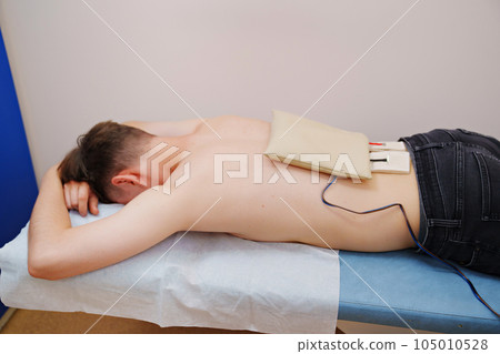 patient with an electrotherapy on the back, electrical stimulation patient with an electrotherapy on the back, electrical stimulation 105010528