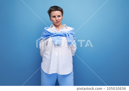 upset young dark-haired woman with sticking hair in a white shirt upset young dark-haired woman with sticking hair in a white shirt 105010836