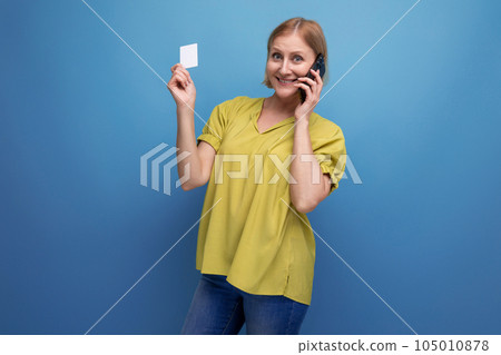blond middle-aged woman holding a plastic card for shopping in her hands 105010878