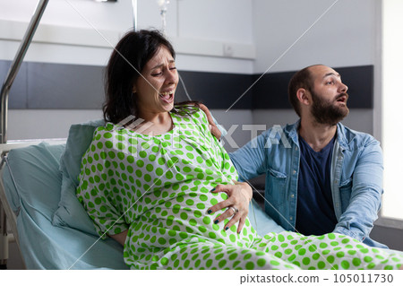 Panicked future father yelling for medic while pregnant woman having painful contractions in hospital ward. Patient with pregnancy getting into labor, asking for medical assistance giving birth Panicked future father yelling for medic while pregnant woman having painful contractions in hospital ward. Patient with pregnancy getting into labor, asking for medical assistance giving birth 105011730
