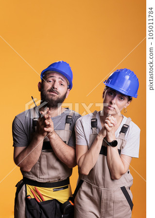 Religious repairman and woman praying to god for good projects, begging for help. Team of engineering experts holding prayer hands to ask for fortune and luck, wearing overalls and helmets. Religious repairman and woman praying to god for good projects, begging for help. Team of engineering experts holding prayer hands to ask for fortune and luck, wearing overalls and helmets. 105011784
