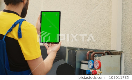 Mechanic ordering new components on green screen mock up tablet for out of order air conditioner after finishing troubleshooting. Expert looking online for hvac system replacement parts 105011785