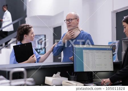 Elderly patient with cervical neck collar explaining symptoms to assistant discussing medication treatment, standing at hospital counter. Injured man waiting to attend checkup visit appointment Elderly patient with cervical neck collar explaining symptoms to assistant discussing medication treatment, standing at hospital counter. Injured man waiting to attend checkup visit appointment 105011828