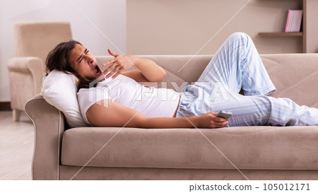 Young lazy man in oversleeping concept at home Young lazy man in oversleeping concept at home 105012171