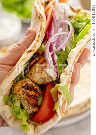 Chicken souvlaki with fresh vegetables on a flatbread 105012892