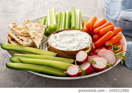 Large snack board with tzatziki dip or sauce and fresh vegetables 105012980