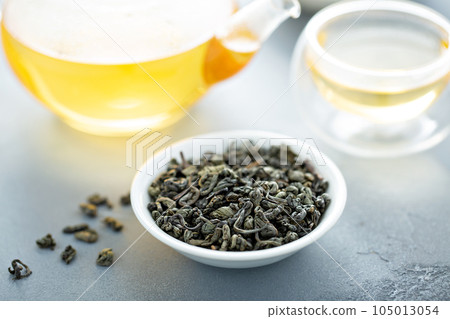 Green loose leaf tea and a teapot 105013054