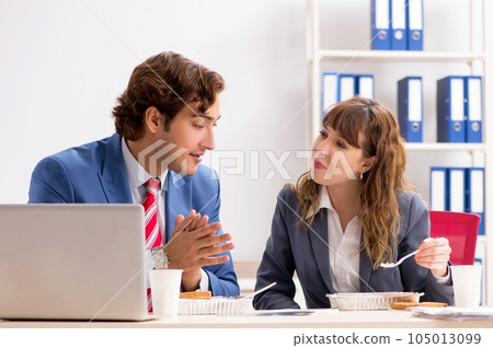 Two colleagues having lunch break at workplace 105013099