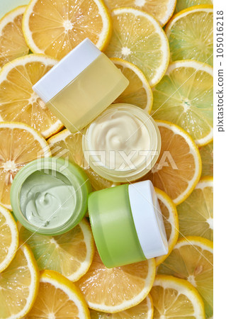 Skin care cosmetics rich in natural vitamin c with lemon slices background. Top view of cream jars unlabeled for design. Lemon essential oil is great for the skin, treating acne and exfoliating. 105016218