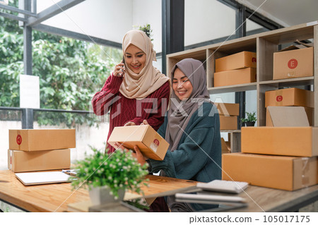Friend muslim female two work business sme online shopping working on laptop computer with parcel box on desk at home, SME online business and delivery concept 105017175