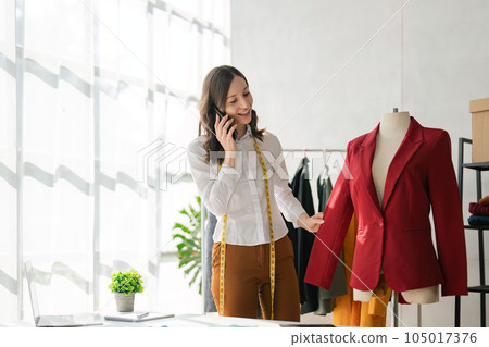 female design at work in her studio with working in office calling to client by smartphone female design at work in her studio with working in office calling to client by smartphone 105017376