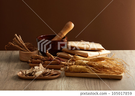 Front view of ginseng roots on tray, rhizoma rhe and codonopsis pilosula displayed on wooden table. Healthy herbs. Advertisement scenes for traditional Chinese medicines 105017859