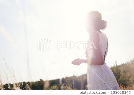Portrait of woman in golden sunset light in outdoor meadow. Springtime and summer lifestyle. Wellbeing and zen like meditation activity in outdoor. Loving life. Portrait of woman in golden sunset light in outdoor meadow. Springtime and summer lifestyle. Wellbeing and zen like meditation activity in outdoor. Loving life. 105018345
