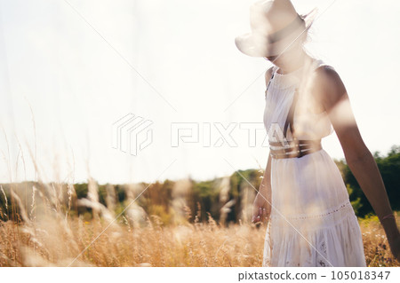 Portrait of woman in golden sunset light in outdoor meadow. Springtime and summer lifestyle. Wellbeing and zen like meditation activity in outdoor. Loving life. Portrait of woman in golden sunset light in outdoor meadow. Springtime and summer lifestyle. Wellbeing and zen like meditation activity in outdoor. Loving life. 105018347