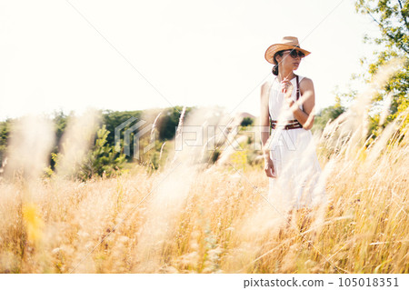 Portrait of woman in golden sunset light in outdoor meadow. Springtime and summer lifestyle. Wellbeing and zen like meditation activity in outdoor. Loving life. 105018351