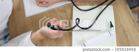 Female doctor using sphygmomanometer checks patient's blood pressure in medical clinic. Female doctor using sphygmomanometer checks patient's blood pressure in medical clinic. 105018458