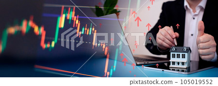 The concept of buying and selling real estate. A man with a model of a house on the background of the forex chart. 105019552