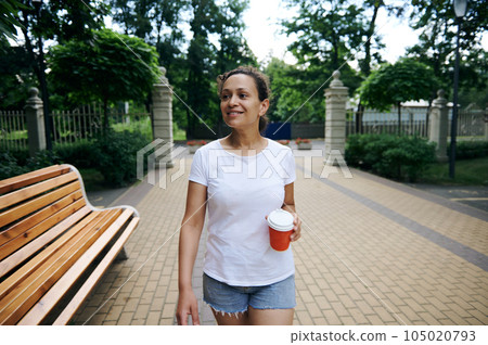 Stunning young woman tourist traveler strolling the street, walking in the park on a beautiful warm summer day 105020793