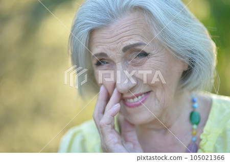 Close up portrait of happy older woman standing outside in summer 105021366