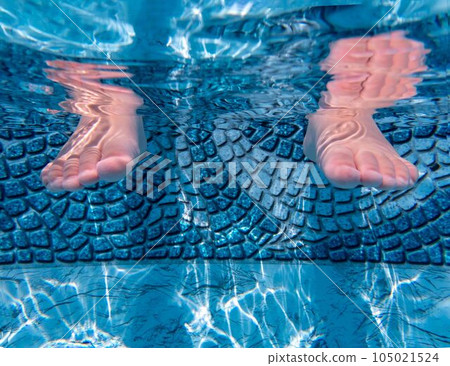 Underwater closeup of toddler child's feet in a sunny clean blue pool 105021524