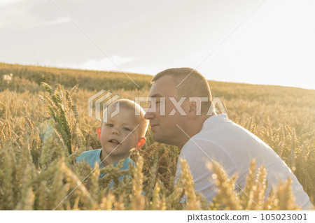 Dad and his little son are having fun walking in a field with ripe wheat. 105023001