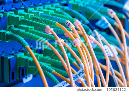 fiber optic cables plugged in network switch panel inside data center 105023122