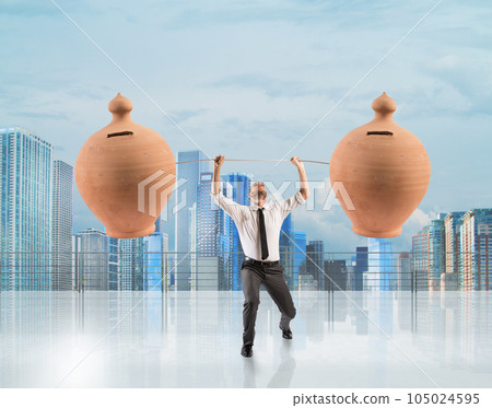 Powerful and determined businessman trains with a barbell with piggy banks Powerful and determined businessman trains with a barbell with piggy banks 105024595
