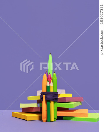 Stationery rocket out of pens on desk on top of pile of sticky notes. purple background. back to school or education and creativity concept. Success achievement. Team work ideas and leadership Stationery rocket out of pens on desk on top of pile of sticky notes. purple background. back to school or education and creativity concept. Success achievement. Team work ideas and leadership 105027551