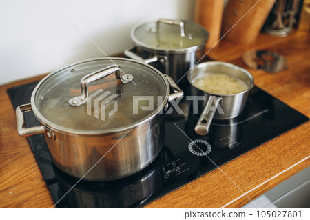 Cooking pots with tasty soup on electric stove in kitchen at the home, food concept Cooking pots with tasty soup on electric stove in kitchen at the home, food concept 105027801