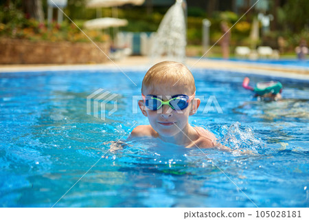 Young boy kid child eight years old splashing in swimming pool having fun leisure activity. Boy happy swimming in a pool. Activities on the pool, children swimming and playing in water, happiness and 105028181