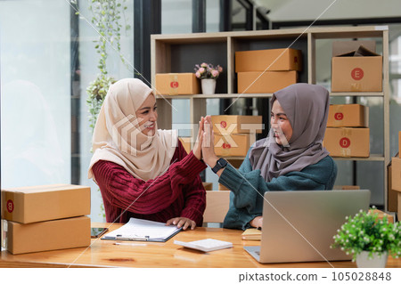 Two woman muslim online business working together, showing a forceful gesture awesome gesture Two woman muslim online business working together, showing a forceful gesture awesome gesture 105028848