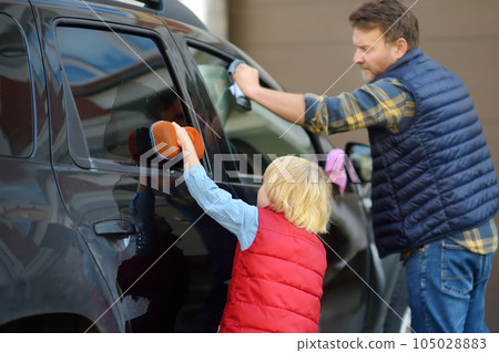 Preschooler boy helping his father washing family car. Little dad helper. Family with children spends time together Preschooler boy helping his father washing family car. Little dad helper. Family with children spends time together 105028883