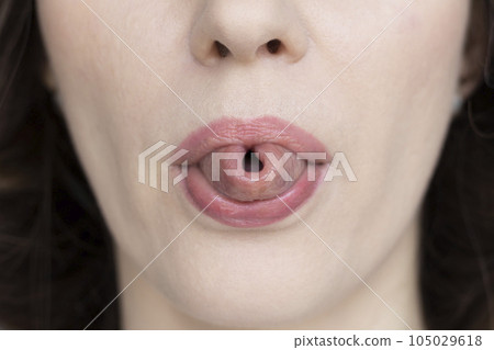 A woman shows her tongue folded into a tube, close-up. A woman shows her tongue folded into a tube, close-up. 105029618