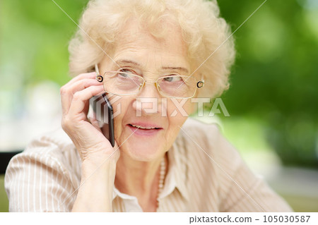 Beautiful senior lady with curly white hair talking on the phone. Communication, talk, gossip. Elderly lady lifestyles. 105030587