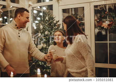 Family drinking homemade eggnog by the Christmas tree having fun Family drinking homemade eggnog by the Christmas tree having fun 105031081