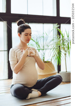 Meditation during pregnancy. Young calm tranquil pregnant woman doing yoga at home Meditation during pregnancy. Young calm tranquil pregnant woman doing yoga at home 105031544