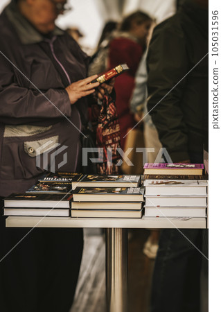 Abstract bookstore, stacks of books on table. Unrecognizable silhouette of elderly woman with book 105031596