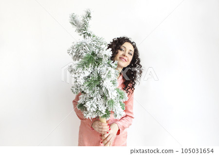 Woman holding small Christmas tree in front of face while standing isolated over white studio background 105031654