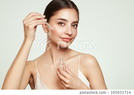Young beautiful woman applying face serum Young beautiful woman applying face serum 105031714