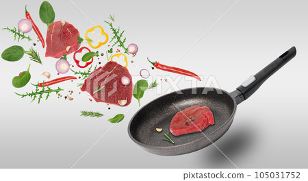Empty black frying pan, beef steaks, spices and rosemary leaves levitate. Cooking steak with vegetable Empty black frying pan, beef steaks, spices and rosemary leaves levitate. Cooking steak with vegetable 105031752