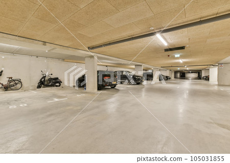 an empty parking with motorcycles parked in the space and two cars parked on the other side of the garages 105031855