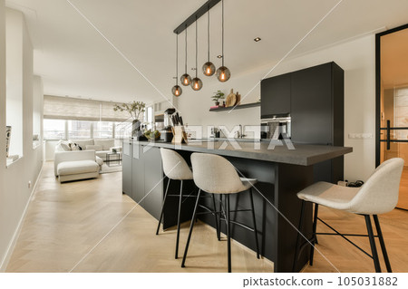 a kitchen and dining area in a modern apartment with white walls, hardwood flooring and black cabinetry on the island 105031882