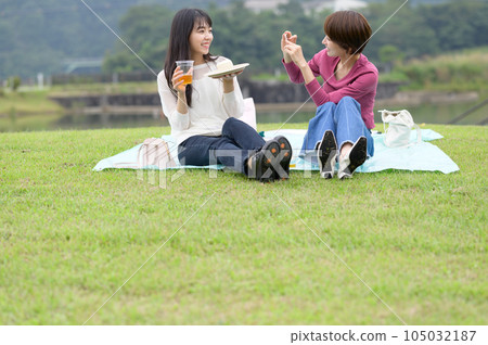 Two women photographing lunch outdoors Two women photographing lunch outdoors 105032187