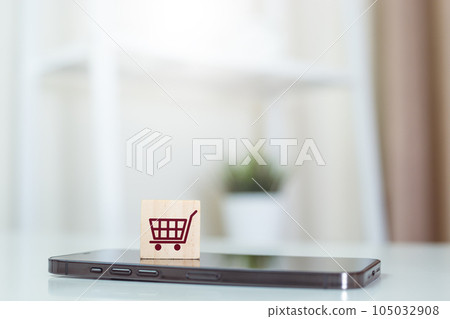 Online shopping concept. wood cube block with shopping cart icons over on mobile phone. Online shopping concept. wood cube block with shopping cart icons over on mobile phone. 105032908