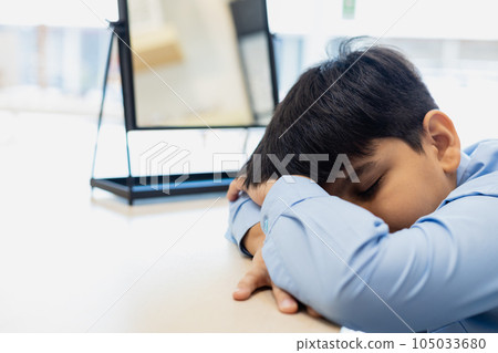 Child boy falls asleep at table classroom. kid pupil education lesson study elementary at desk. 105033680